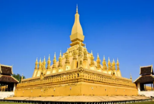 A large gold building with a pointed top with That Luang in the background

AI-generated content may be incorrect.